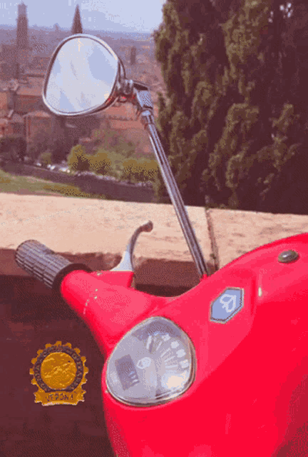 a red vespa scooter is parked on a ledge