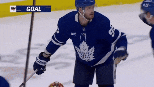 a hockey player in a toronto maple leafs jersey holds a stick