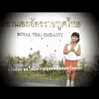 a little girl is standing in front of a sign that says royal thai embassy