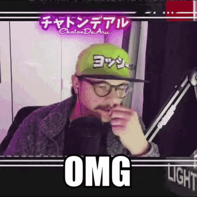 a man wearing glasses and a hat is talking into a microphone and the word omg is above him
