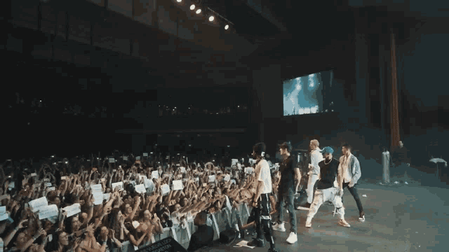 a group of people are standing on a stage with smoke coming out of them and a crowd behind them