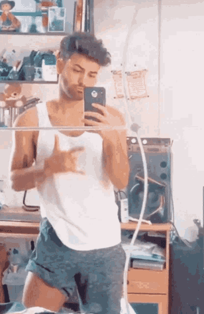a man in a white tank top is taking a picture of himself