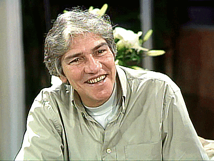 a man with gray hair is smiling in front of a bouquet of white flowers