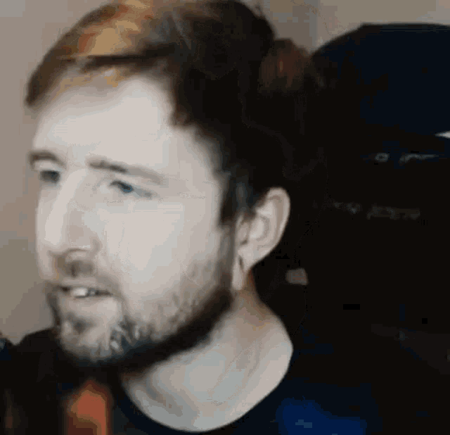 a man with a beard is sitting in a chair and looking at something .