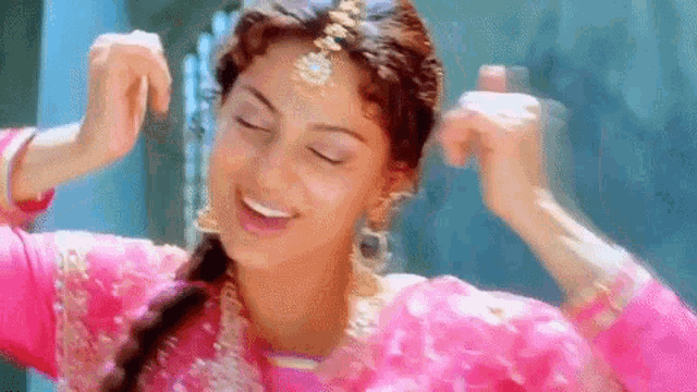 a woman in a pink dress is dancing with her hands in the air and smiling .