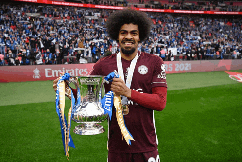 a soccer player holds up a trophy with emirates written on the back
