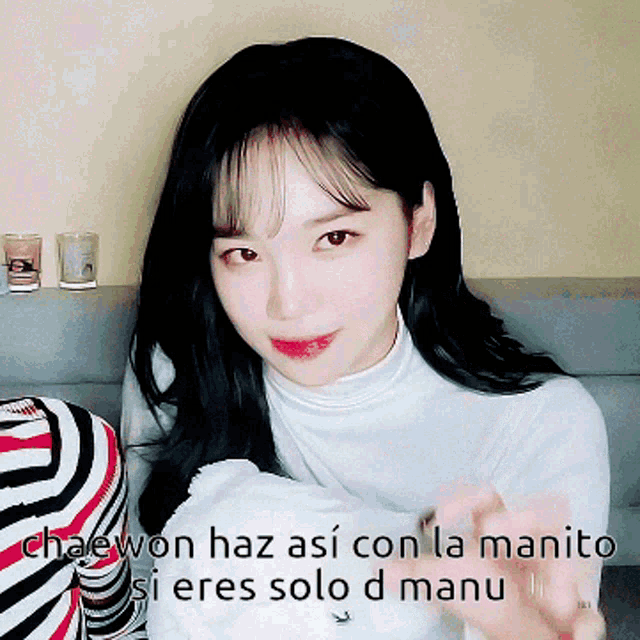a woman sitting on a couch with the words chaewon haz así con la manito si eres solo d manu on the bottom