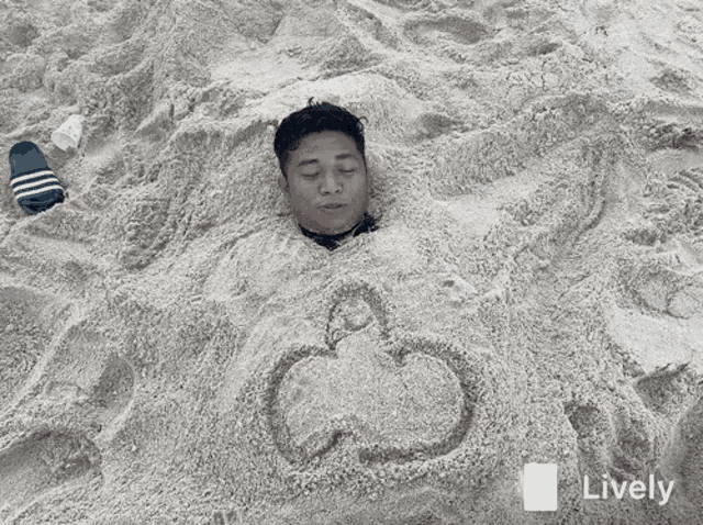 a man is buried in sand with a heart drawn in it