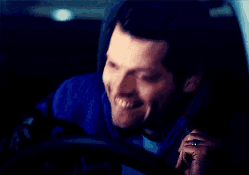 a man in a blue jacket is smiling while sitting in a car .