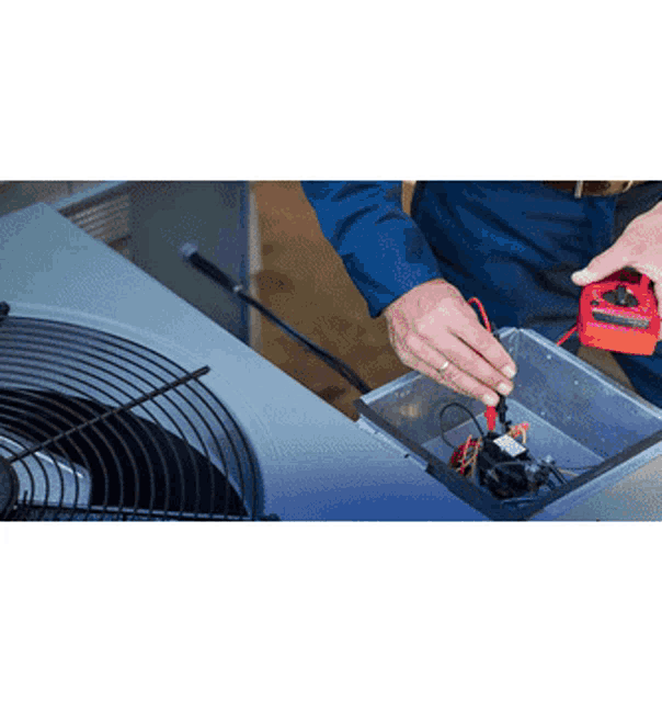 a man is working on an air conditioner while holding a red multimeter