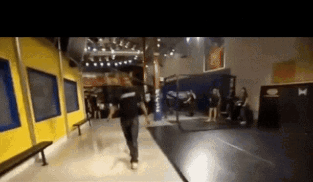 a blurry photo of a person walking in a hallway with a hurley logo on the wall