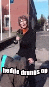 a woman in a black jacket is riding a man in a wheelchair with the words " hedde drungs op " above her