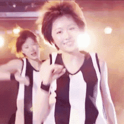 a woman in a black and white striped shirt is dancing on a stage