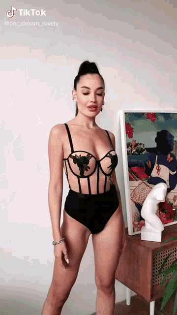 a woman in a bodysuit is standing in front of a painting .