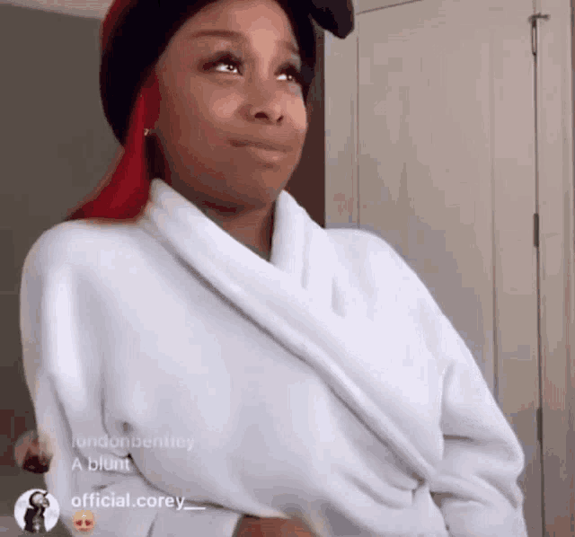 a woman with red hair is wearing a white robe and a black hat