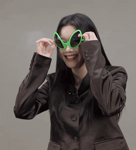 a woman wearing a pair of green alien sunglasses makes a face