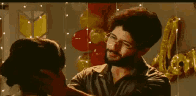 a man and a woman are standing next to each other in a room with balloons .