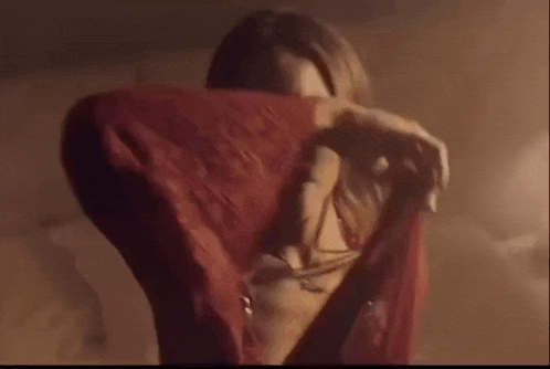 a woman in a red dress is covering her face with a red scarf .