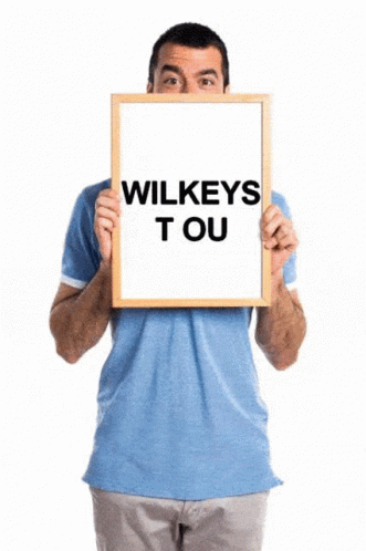 a man in a blue shirt holds a sign that says wilkeys tou