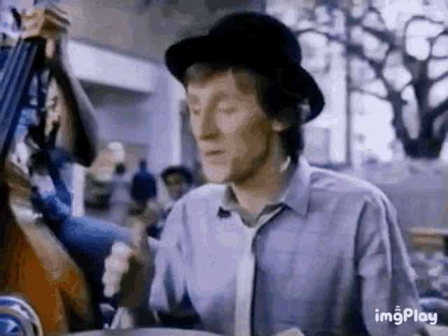 a man wearing a hat and tie is playing a double bass in an advertisement .