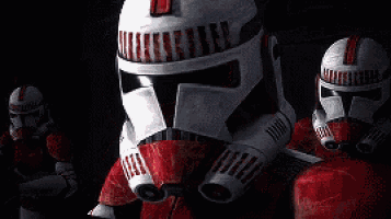 a group of red and white stormtroopers are standing next to each other .