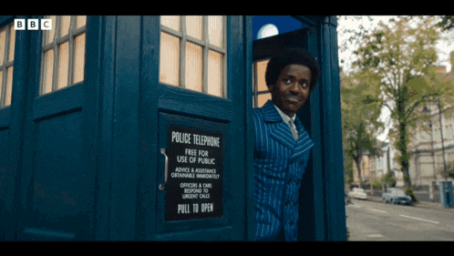 a man in a striped suit is standing in a police telephone booth