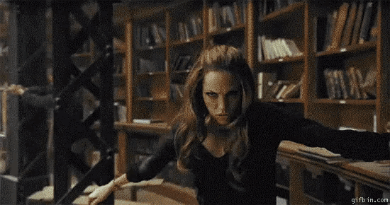 a person is holding a wand in a library with a smoke coming out of it .