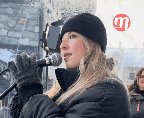 a woman singing into a shure microphone in front of a sign that says audio