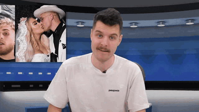 a man wearing a white patagonia t-shirt is standing in front of a screen