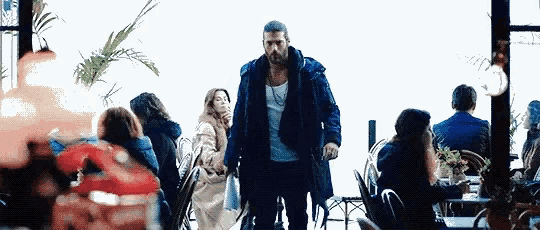 a man in a blue coat is walking through a restaurant filled with people .