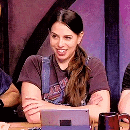 a woman wearing a harley davidson t-shirt smiles while sitting at a table