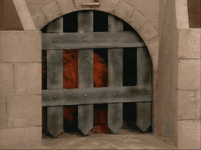 a lion is behind bars in a brick building