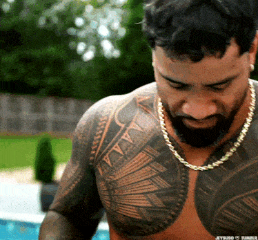 a shirtless man with a tattoo on his chest is wearing a gold chain necklace