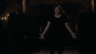 a crowd of people are dancing in a dark room with a blue light behind them .