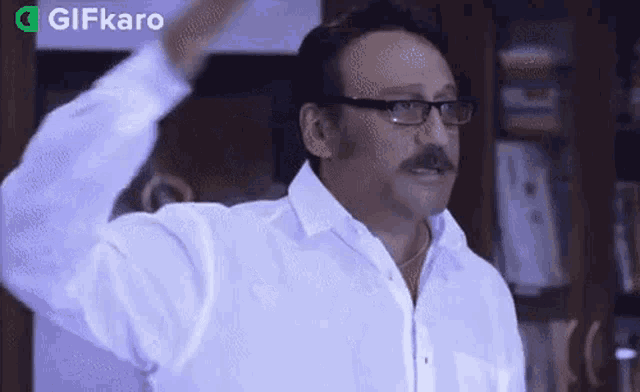 a man wearing glasses and a white shirt is standing in a room .