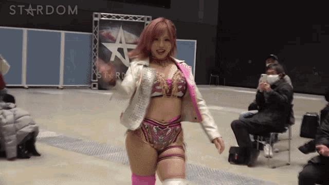 a woman in a wrestling outfit walks in front of a stardom sign