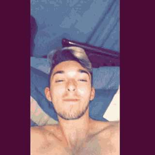 a man without a shirt is laying on a bed with his eyes closed