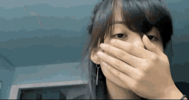 a woman is covering her face with her hand while wearing earrings
