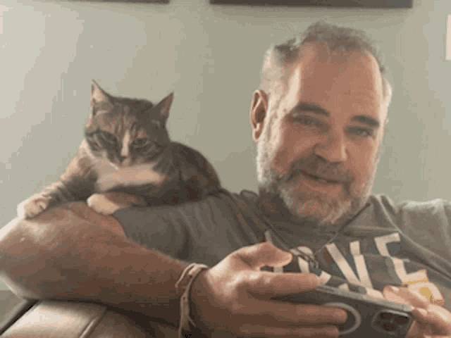 a man is holding a cat on his lap while wearing a shirt that says love