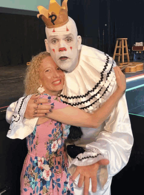 a woman is hugging a clown who has a crown on his head
