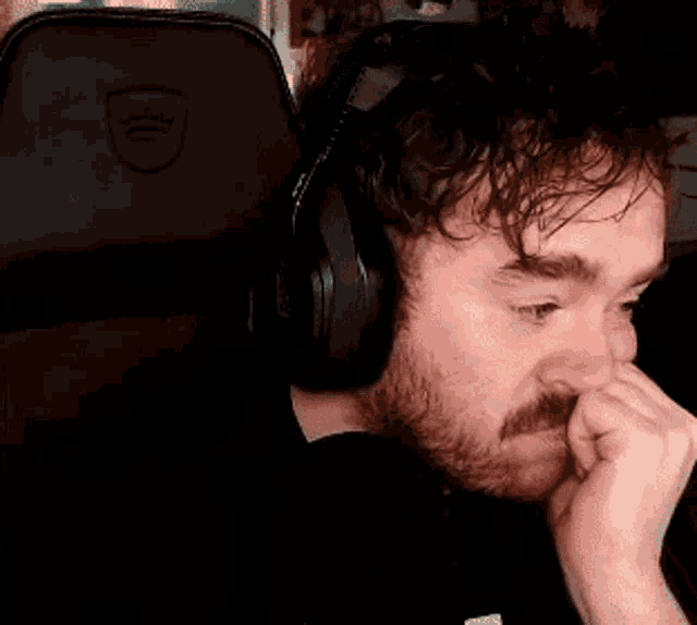 a man wearing headphones and covering his face with his hand