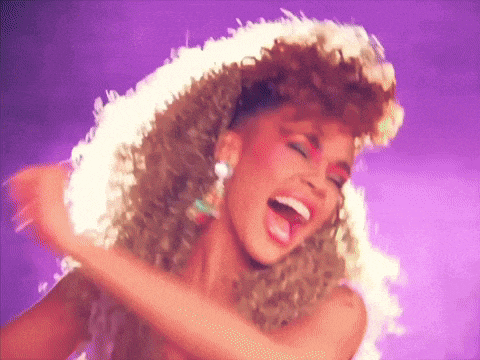 a woman with curly hair is laughing with her mouth open