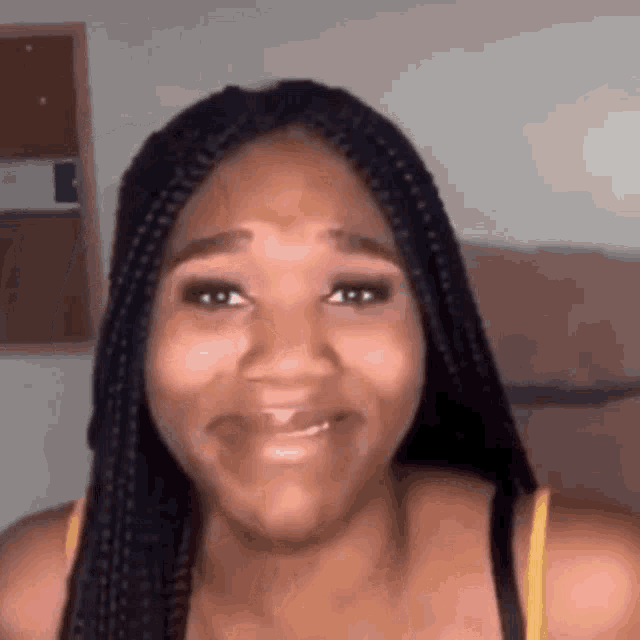 a woman with braids is smiling and making a face .