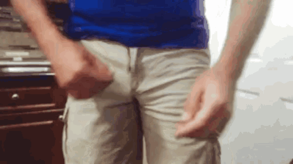 a man in a blue shirt and khaki shorts is standing in front of a counter