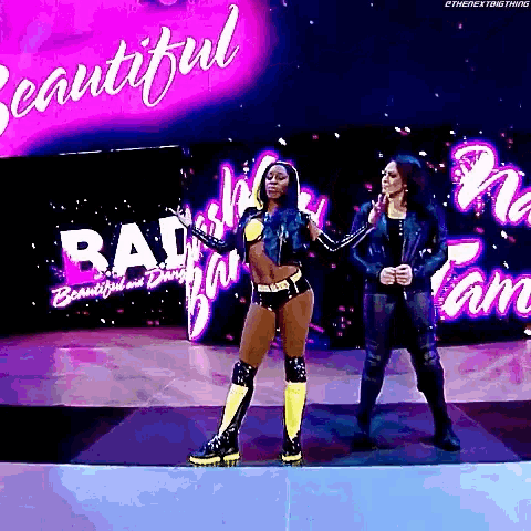 two female wrestlers are standing on a stage in front of a sign that says beautiful