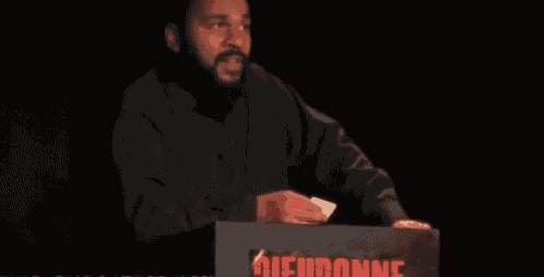 a man with a beard and mustache is smiling in a dark room