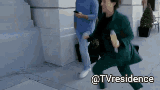 a woman in a green suit is running down a sidewalk with the words @tvresidence written on the bottom