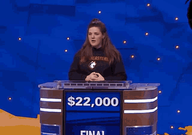 a woman stands at a podium with a $ 22,000 prize