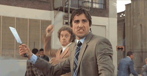 a man in a suit and tie holds a knife in his hand