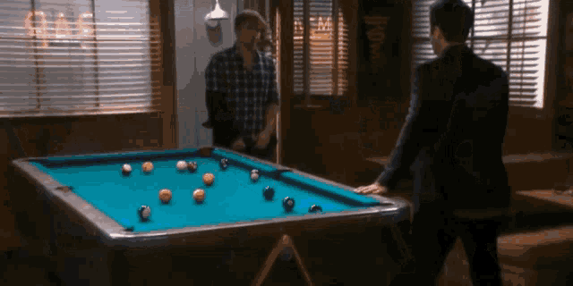 two men are playing pool in front of a sign that says ' bar ' on it
